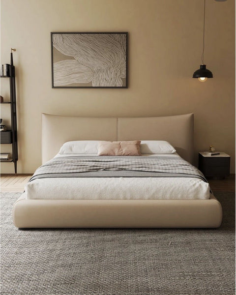 A minimalist bedroom showcases a beige "Chanel" Bed Frame with striped bedding, next to a nightstand with a lamp and abstract art. The decor is enhanced by microfiber leather touches, while a gray rug spans the polished wooden floor.