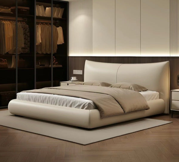 A modern bedroom with a minimalist design features the "Chanel" Bed Frame, crafted from microfiber leather and supported by a hardwood structure. The space boasts a neutral palette and an open closet with hanging clothes.