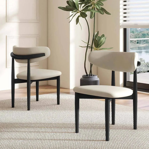 A set of two Mid-Century Modern Dining Chairs with solid wood frames and custom upholstery are placed on a textured rug in a bright room featuring a potted plant and large window.